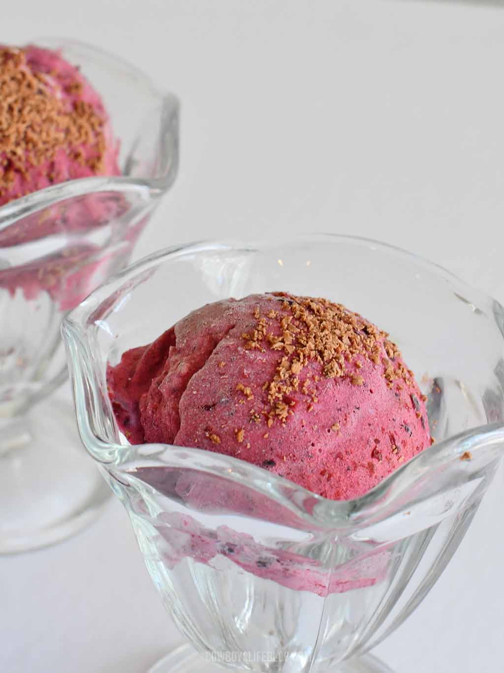 Mixed berry ice cream topping with chocolate shavings in a glass bowl
